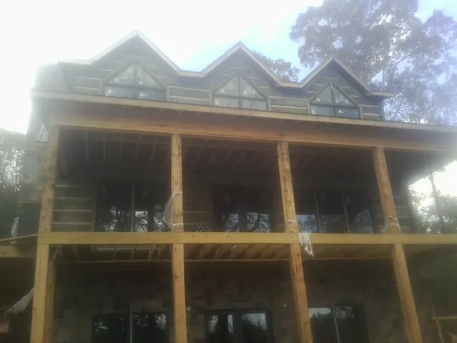 Dormers and porch framing on a large log home under construction — Roof Coating work by our crew in Kinsman