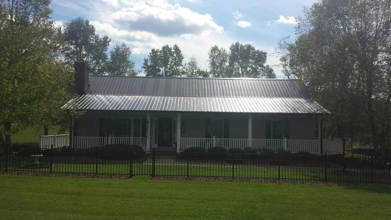 Gray metal roof on a brick ranch with a full width front porch — Gutter Guard Installation work by our crew in Kinsman