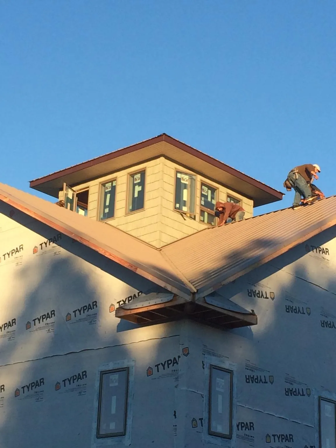 Roofers working around a rooftop cupola on a new metal roof at sunset — Roof Waterproofing in Kinsman by Roofing Brothers